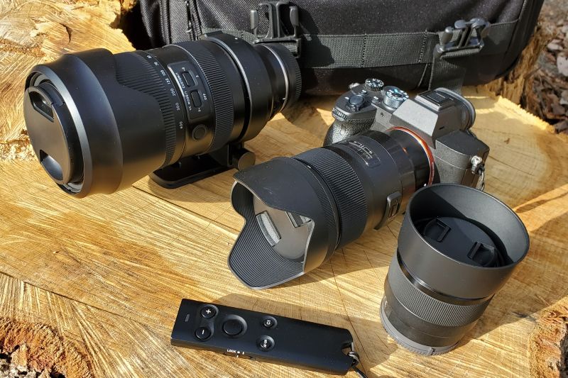 野外の椅子に置かれた一眼レフカメラと予備のレンズ