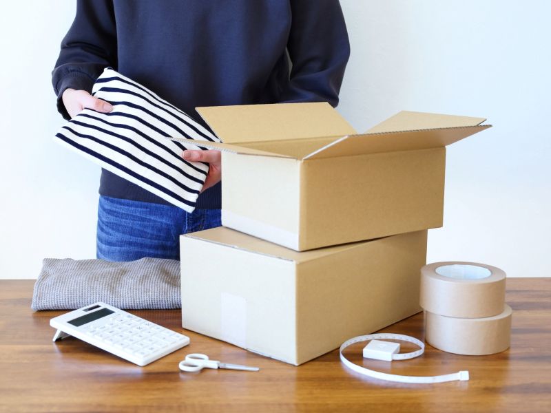 段ボールに洋服を入れて郵送しようとしている女性