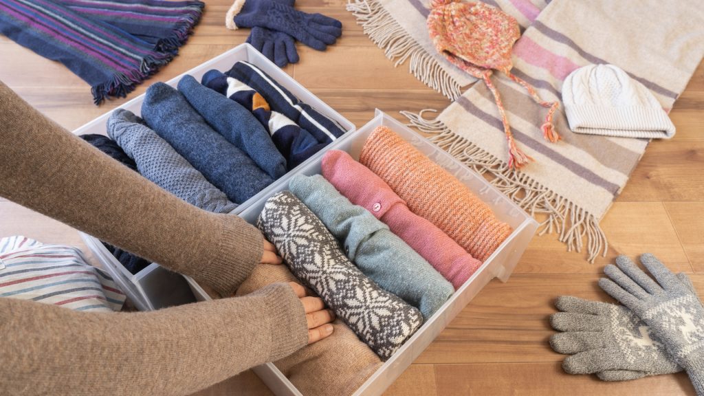 マフラーなどの冬服を収納ケースにしまっている様子
