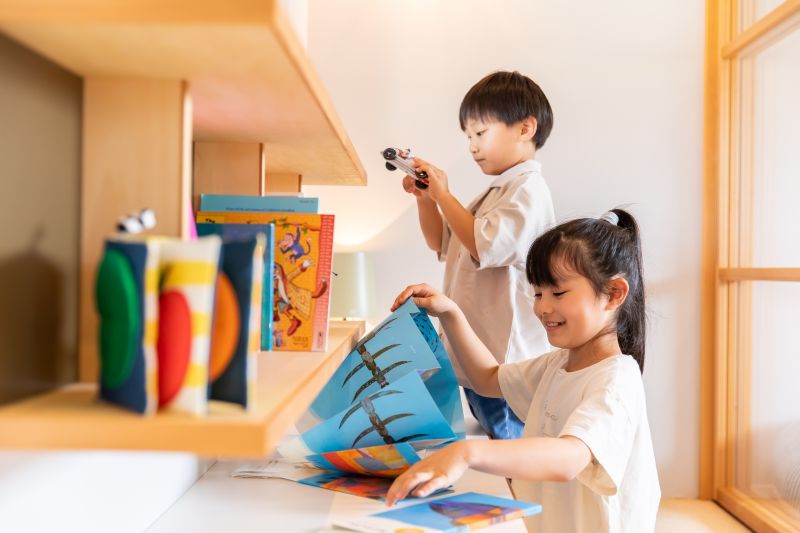 ローシェルフから絵本を取り出す男の子と女の子