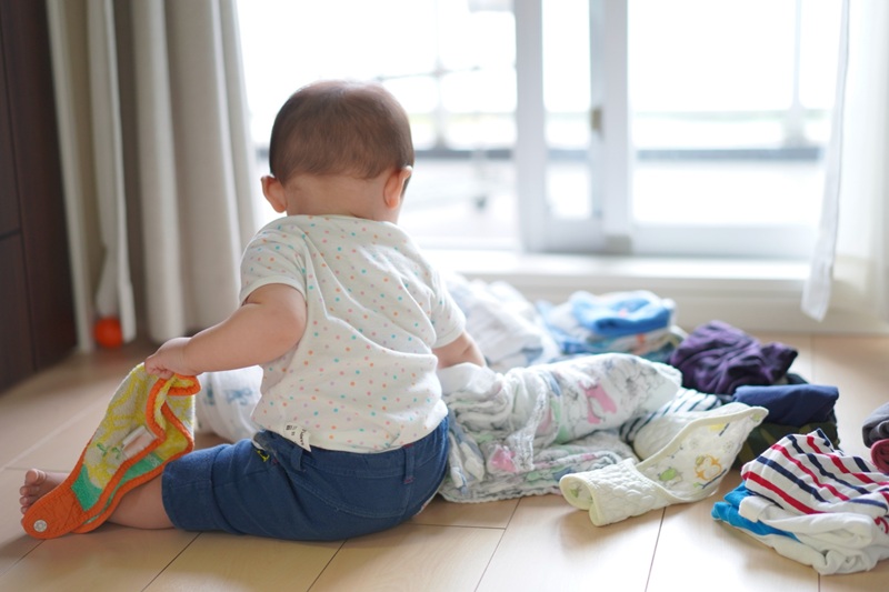 ベビー服に触れようとしている赤ちゃん