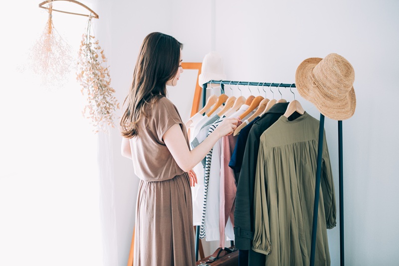 部屋のオープンクローゼットで洋服を選ぶ女性